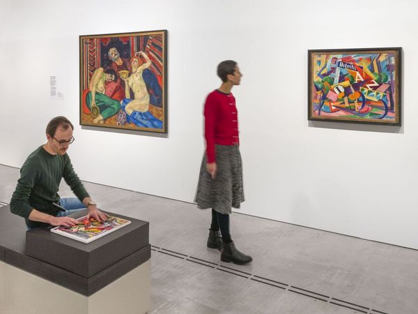 Museum_Berlin_Barrierefreiheit Zwei Menschen im Ausstellungsraum. Eine Person betastet ein Tastmodell, eine andere betrachet ein Gemälde.